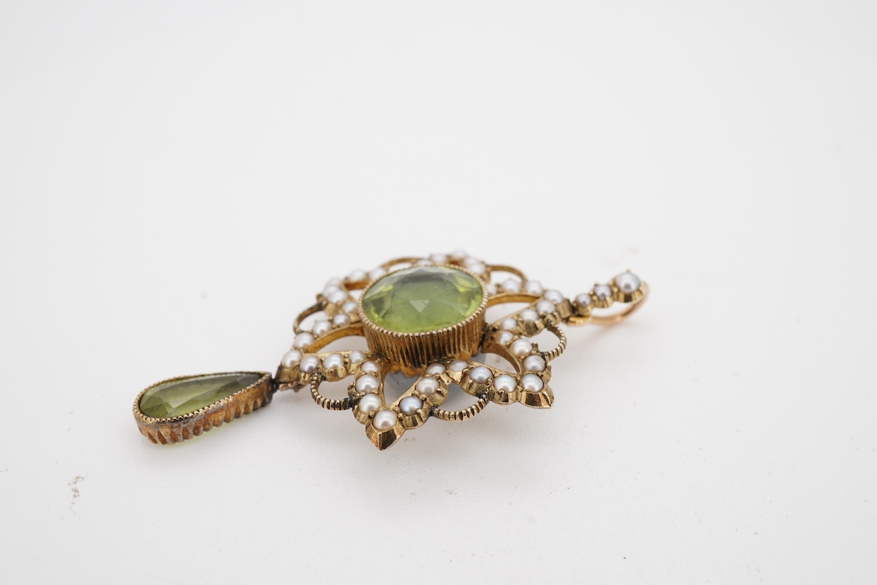An Edwardian 15ct, peridot and seed pearl cluster pendant, set with circular and pear cut peridot, overall 39mm.